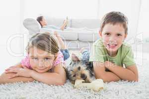 Siblings lying on rug with yorkshire terrier smiling at camera