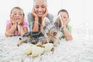 Siblings lying on rug looking at their yorkshire terrier with mo