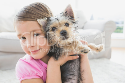 Smiling little girl holding her yorkshire terrier puppy