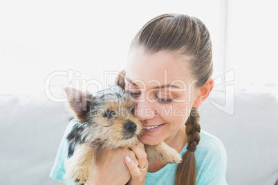 Smiling woman cuddling her yorkshire terrier puppy