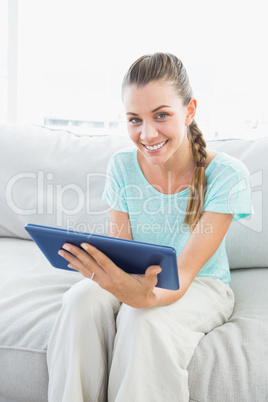 Smiling woman sitting on couch using tablet pc