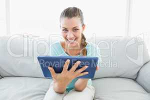 Cheerful woman sitting on couch using tablet pc