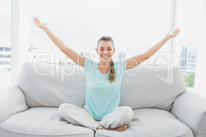 Smiling woman sitting on couch with arms outstretched