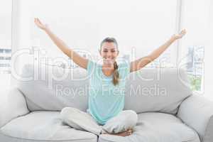 Smiling woman sitting on couch with arms outstretched