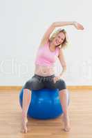 Fit blonde pregnant woman sitting on exercise ball