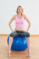 Thinking blonde pregnant woman sitting on exercise ball