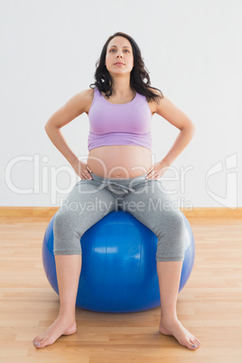 Pregnant woman sitting on blue exercise ball