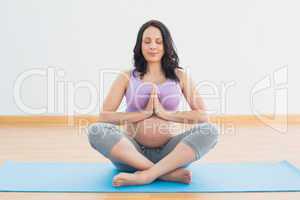 Pregnant woman sitting on mat in lotus pose