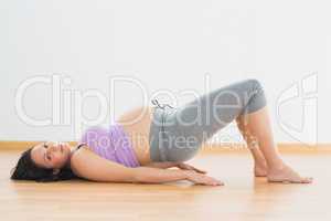 Pregnant brunette lying on floor in bridge pose