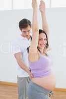 Happy pregnant woman doing yoga with a personal trainer