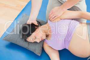 Masseur moving pregnant womans neck and shoulder