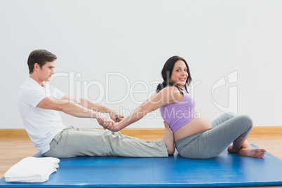 Masseur stretching pregnant womans arms and shoulders