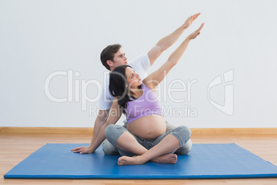 Trainer sitting with pregnant woman doing yoga