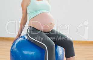 Pregnant woman sitting on blue exercise ball