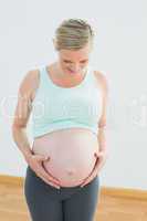 Blonde pregnant woman looking down at her belly