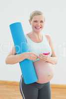 Happy pregnant woman holding exercise mat sending a text message