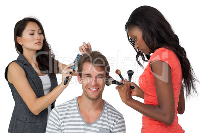 Assistants applying make-up to male model