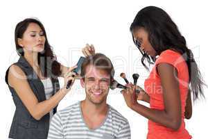 Assistants applying make-up to male model