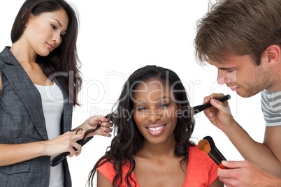 Assistants applying make-up to a female model
