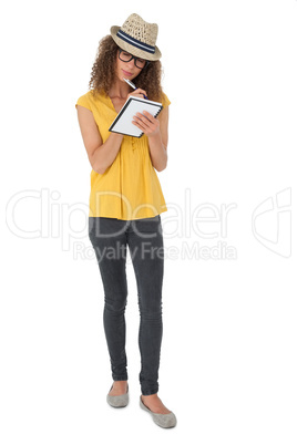 Serious cool young woman writing in notepad