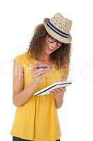 Cheerful young woman writing in notepad