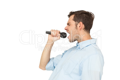 Side view of a young man singing into microphone