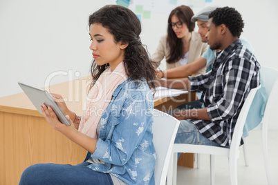 Woman using digital tablet with group in meeting at office