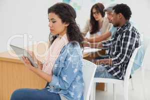 Woman using digital tablet with group in meeting at office