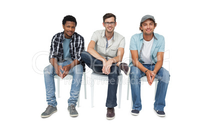 Portrait of three cool young men sitting on chairs