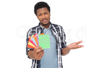 Portrait of a confused man holding colorful papers