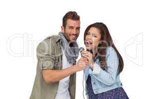 Portrait of a young couple singing into microphone