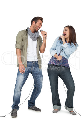 Full length of a couple singing into microphones