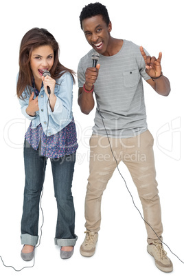 Portrait of a young couple singing into microphones