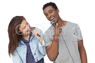 Young couple singing into microphones