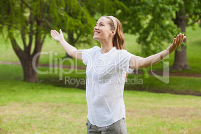 Smiling woman with arms outstretched at park