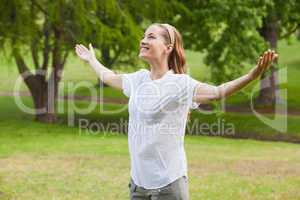 Smiling woman with arms outstretched at park