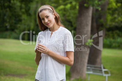 Smiling young woman holding a flower at park