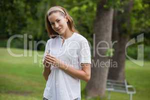 Smiling young woman holding a flower at park