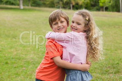 Two smiling kids hugging at park