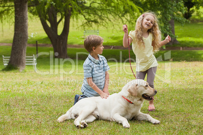 Two happy kids with pet dog at park