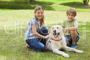 Portrait of kids playing with pet dog at park