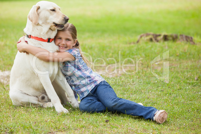 Young girl hugging pet dog at park
