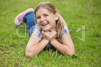 Happy young girl lying on grass at park