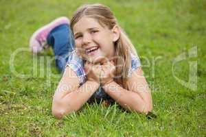 Happy young girl lying on grass at park