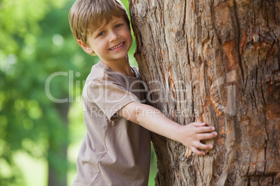 Young boy hugging a tree at park