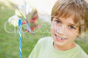 Close-up of smiling boy holding pinwheel in park