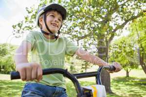 Smiling young boy riding bicycle at park