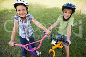 Smiling siblings riding bicycles at park