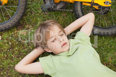 Boy resting besides bicycle at park