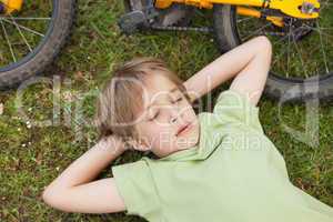 Boy resting besides bicycle at park